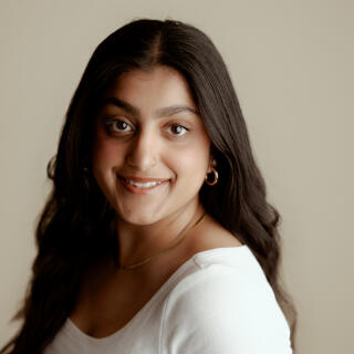 A smiling woman in a white shirt and gold jewelry